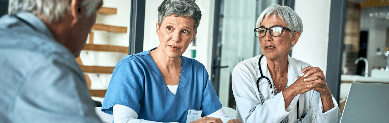 Two healthcare professionals in discussion with a patient in a clinical office